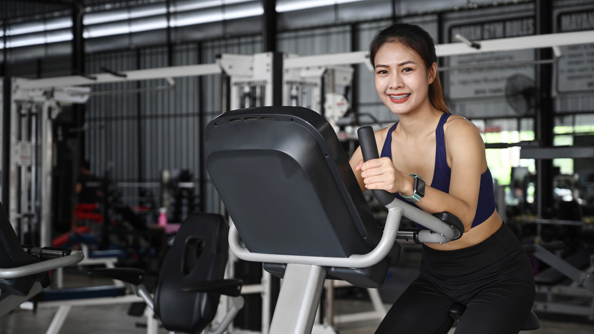smiling fit young woman cycling machines in sports club .jpg